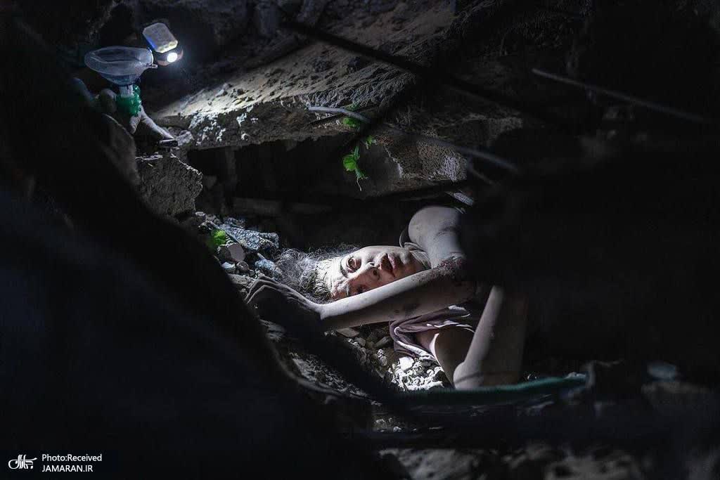 دختری که زیر آوار پس از بمباران توسط هواپیمای اسراییلی گیر گرده است